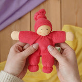 Nanchen Natur Pimpel Waldorf doll in cherry red in an adult's hands in the Babipur playroom. 