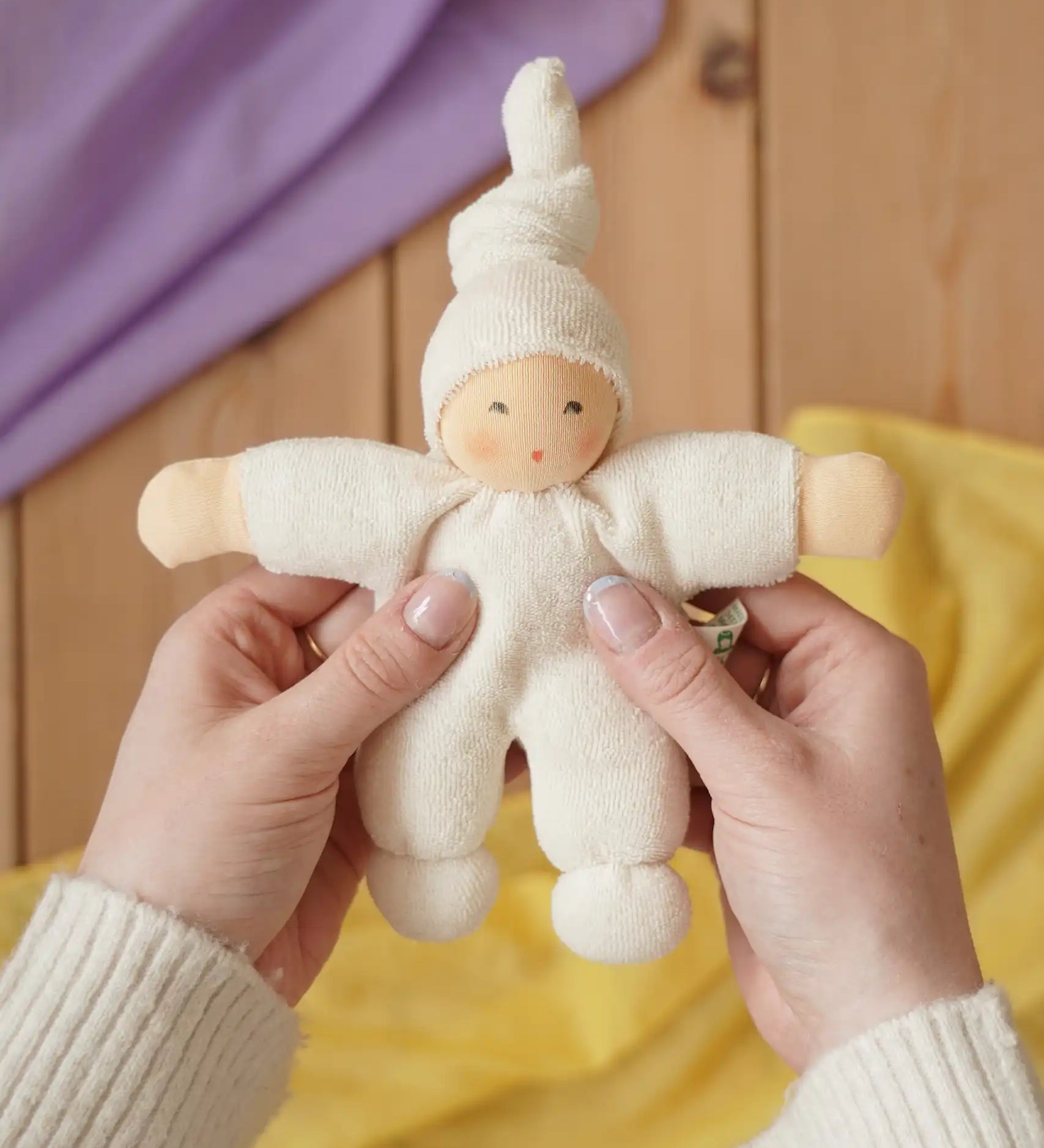 Nanchen Natur Pimpel Waldorf doll in natural in an adult's hands in the Babipur playroom. 