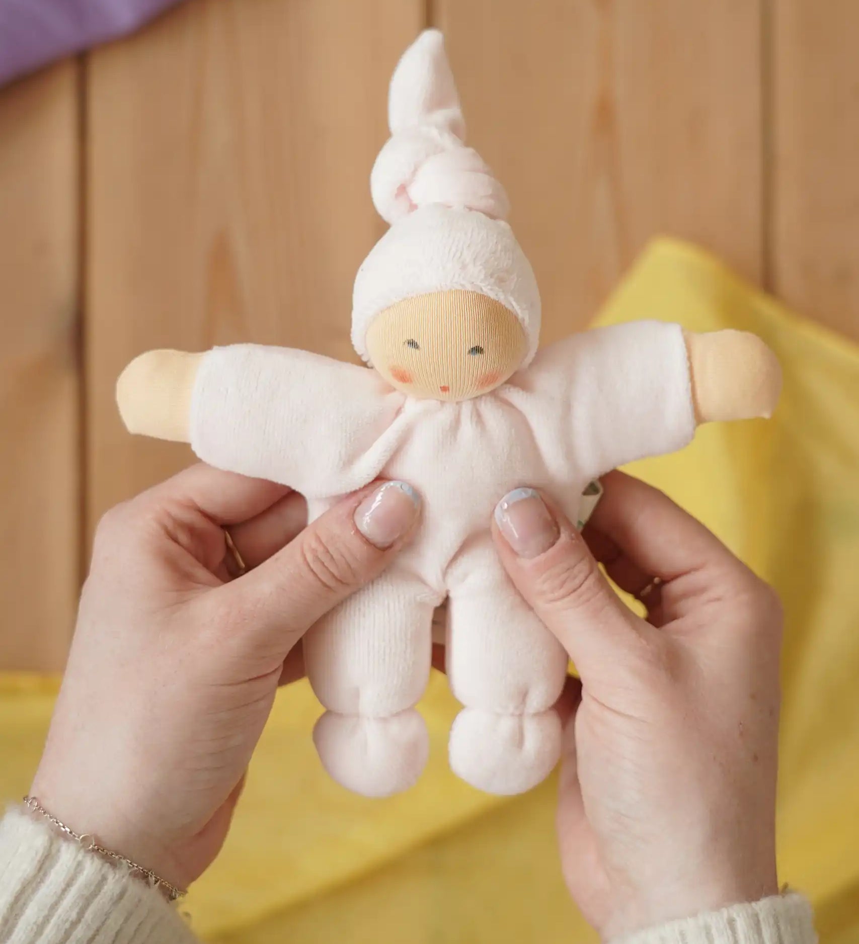 Nanchen Natur Pimpel Waldorf doll in pastel pink in an adult's hands in the Babipur playroom. 