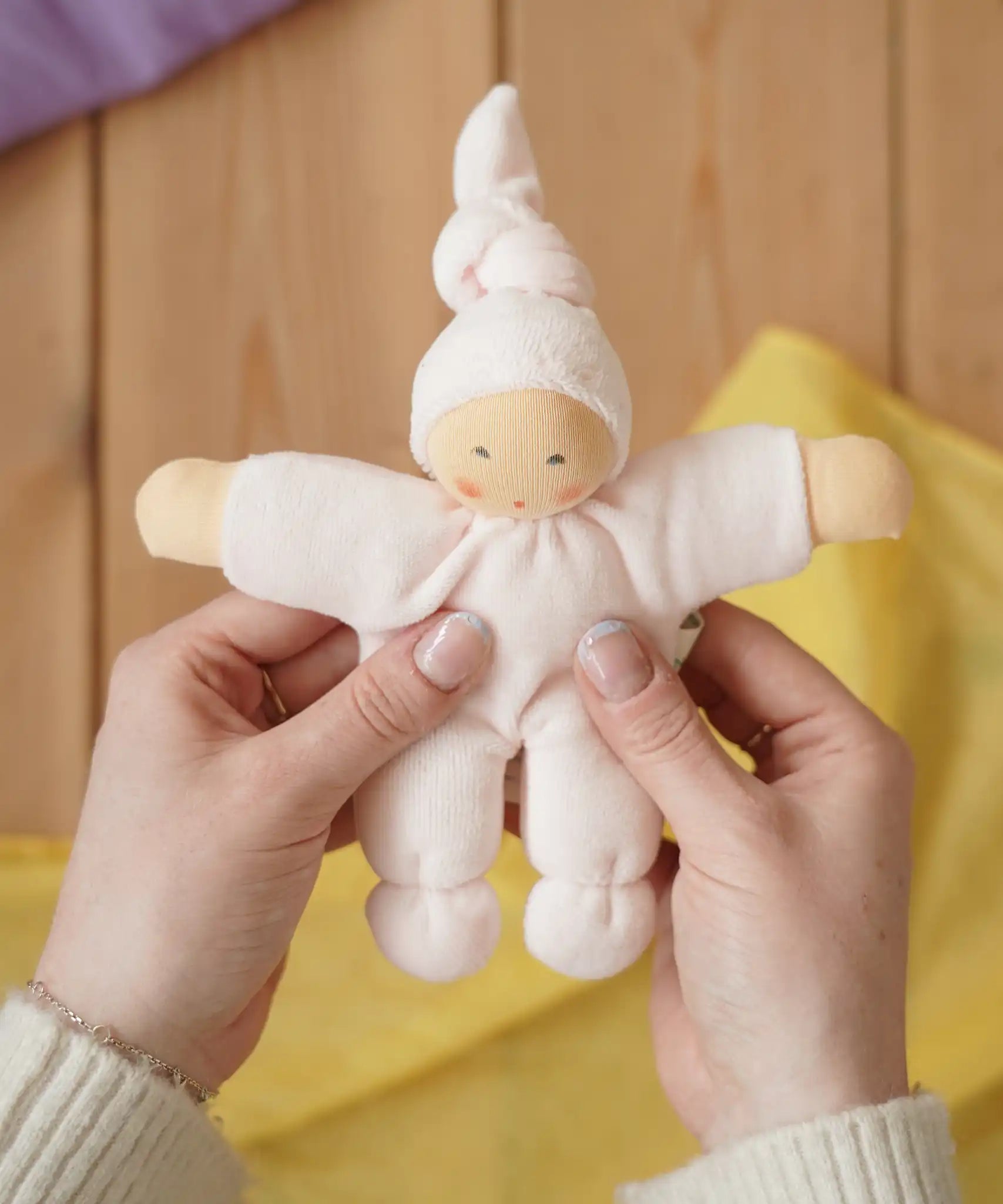 Nanchen Natur Pimpel Waldorf doll in pastel pink in an adult's hands in the Babipur playroom. 