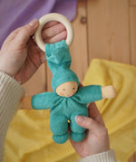 A turquoise coloured Nanchen Pimpel Waldorf Doll Ring Comforter in an adult's hands in the Babipur playroom. 