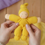 Nanchen Natur Pimpel Waldorf doll in yellow in an adult's hands in the Babipur playroom. 
