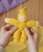 Nanchen Natur Pimpel Waldorf doll in yellow in an adult's hands in the Babipur playroom. 