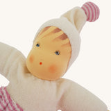 A close up of teh face on the Nanchen Möpschen Waldorf Doll. The doll has a Pink Striped trousers and a matching bobble on her hat.