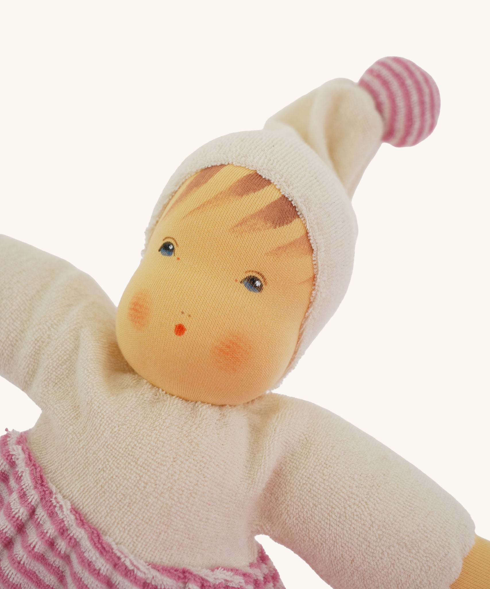 A close up of teh face on the Nanchen Möpschen Waldorf Doll. The doll has a Pink Striped trousers and a matching bobble on her hat.