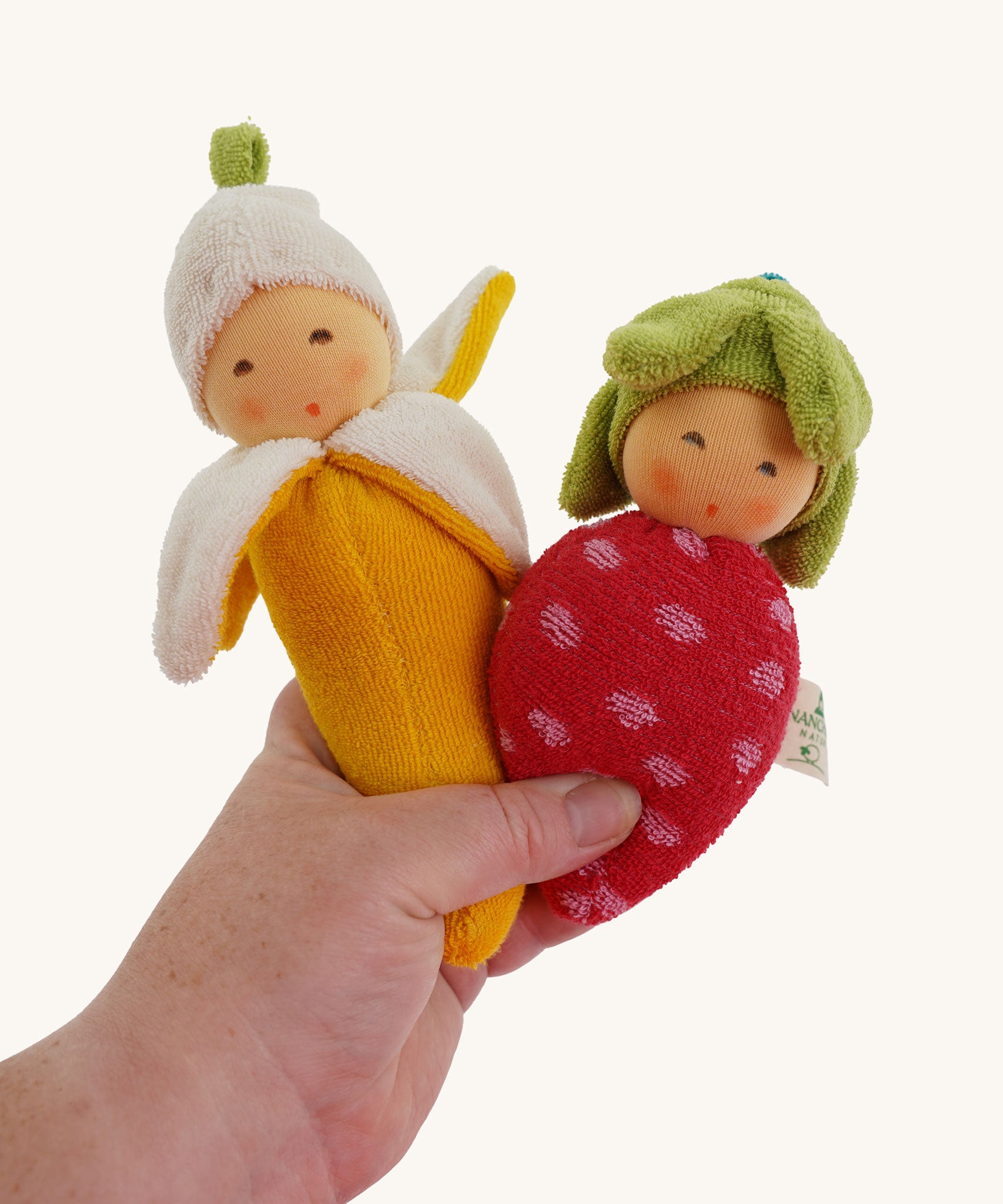 Nanchen banana and strawberry Baby Rattle Dolls in an adult's hand. 