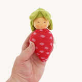 A Nanchen Baby Rattle Doll in an adult's hand. These handcrafted toys are made made natural and organic materials.
