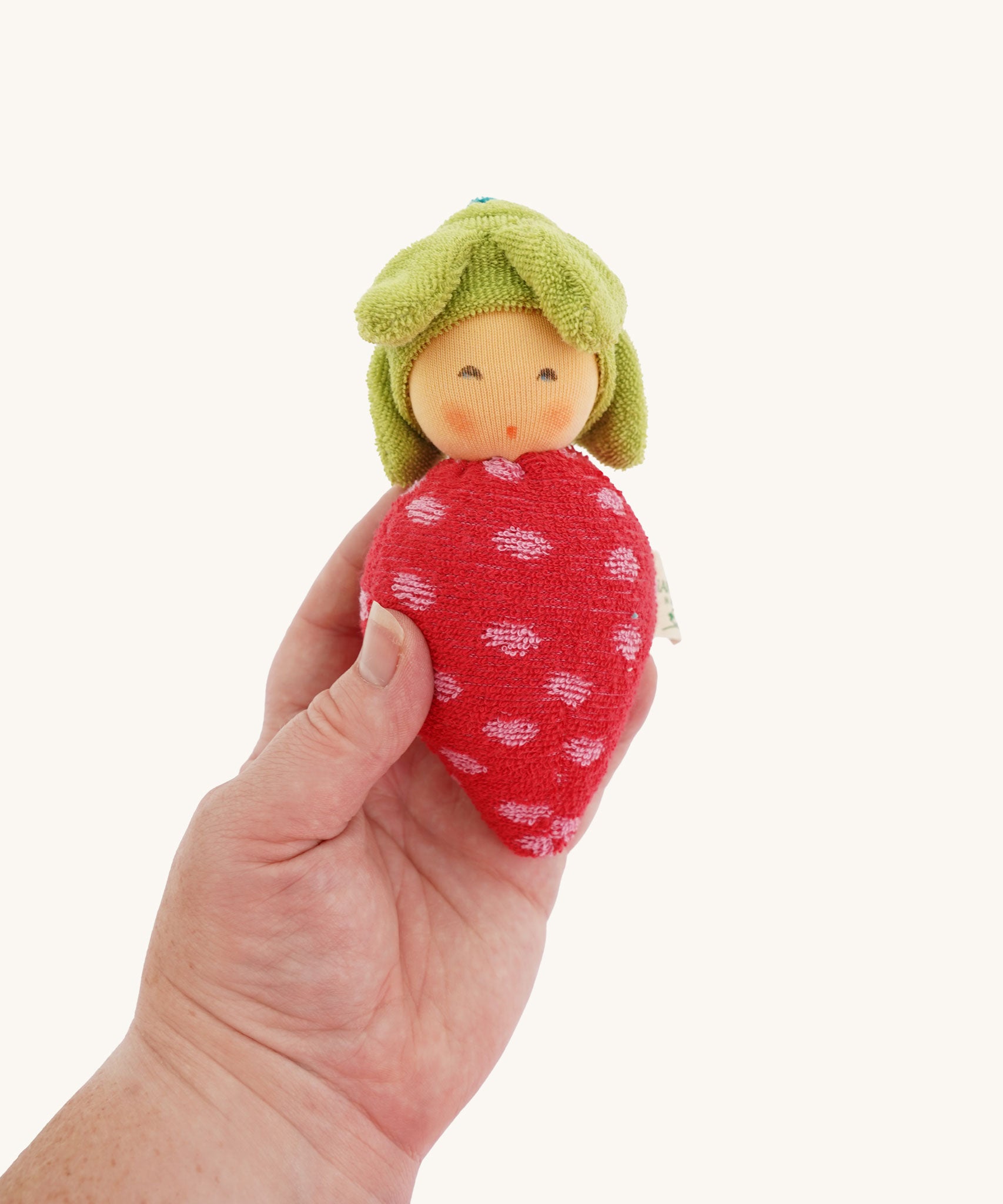A Nanchen Baby Rattle Doll in an adult's hand. These handcrafted toys are made made natural and organic materials.