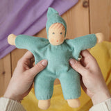 Nanchen Natur Waldorf cuddle doll in turquoise in an adult's hands in the Babipur playroom. 