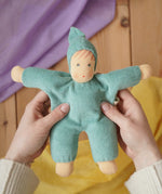 Nanchen Natur Waldorf cuddle doll in turquoise in an adult's hands in the Babipur playroom. 