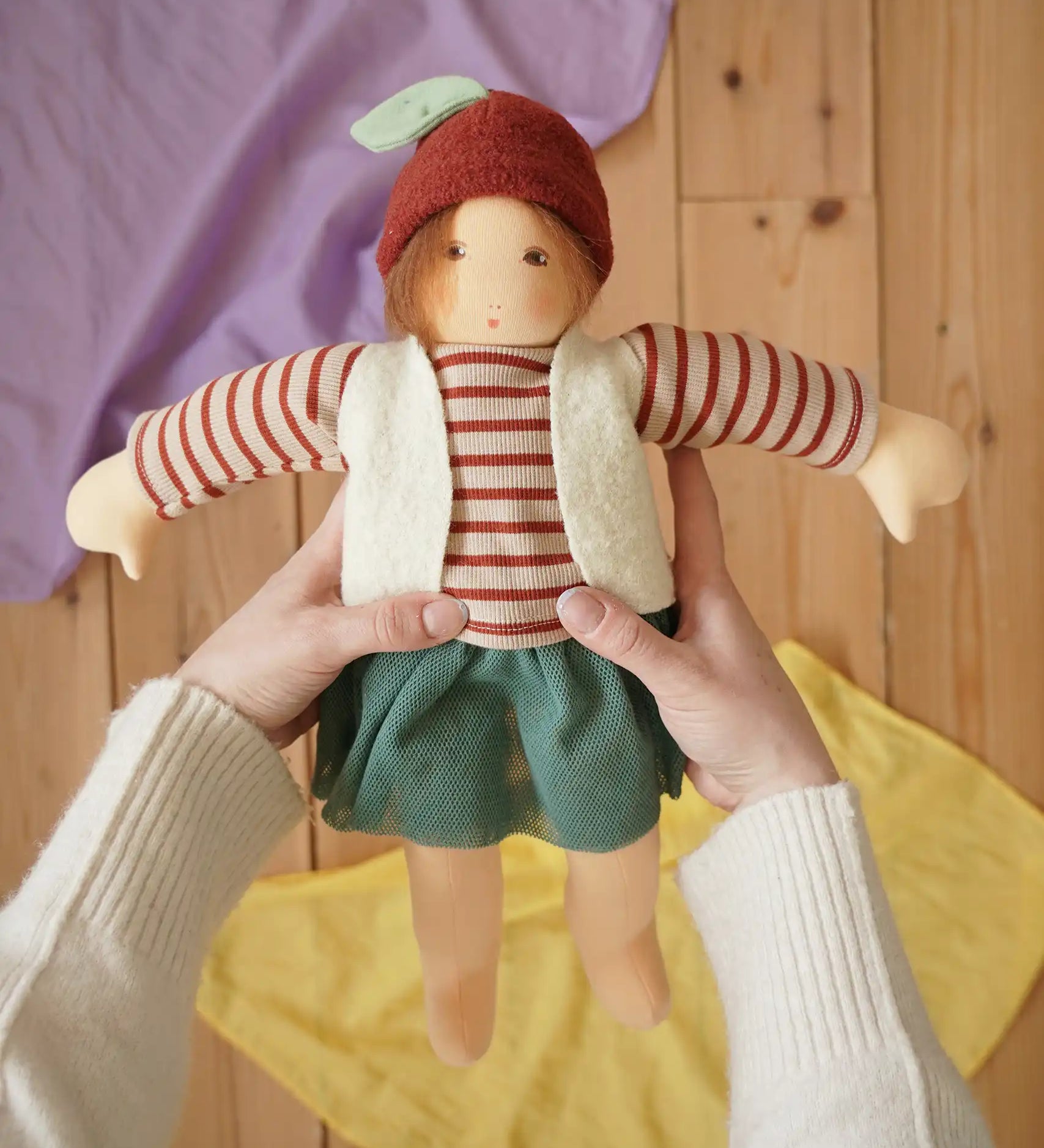 Nanchen Natur dress-up Waldorf doll chestnut child Karlotta in an adults hands in the Babipur playroom.