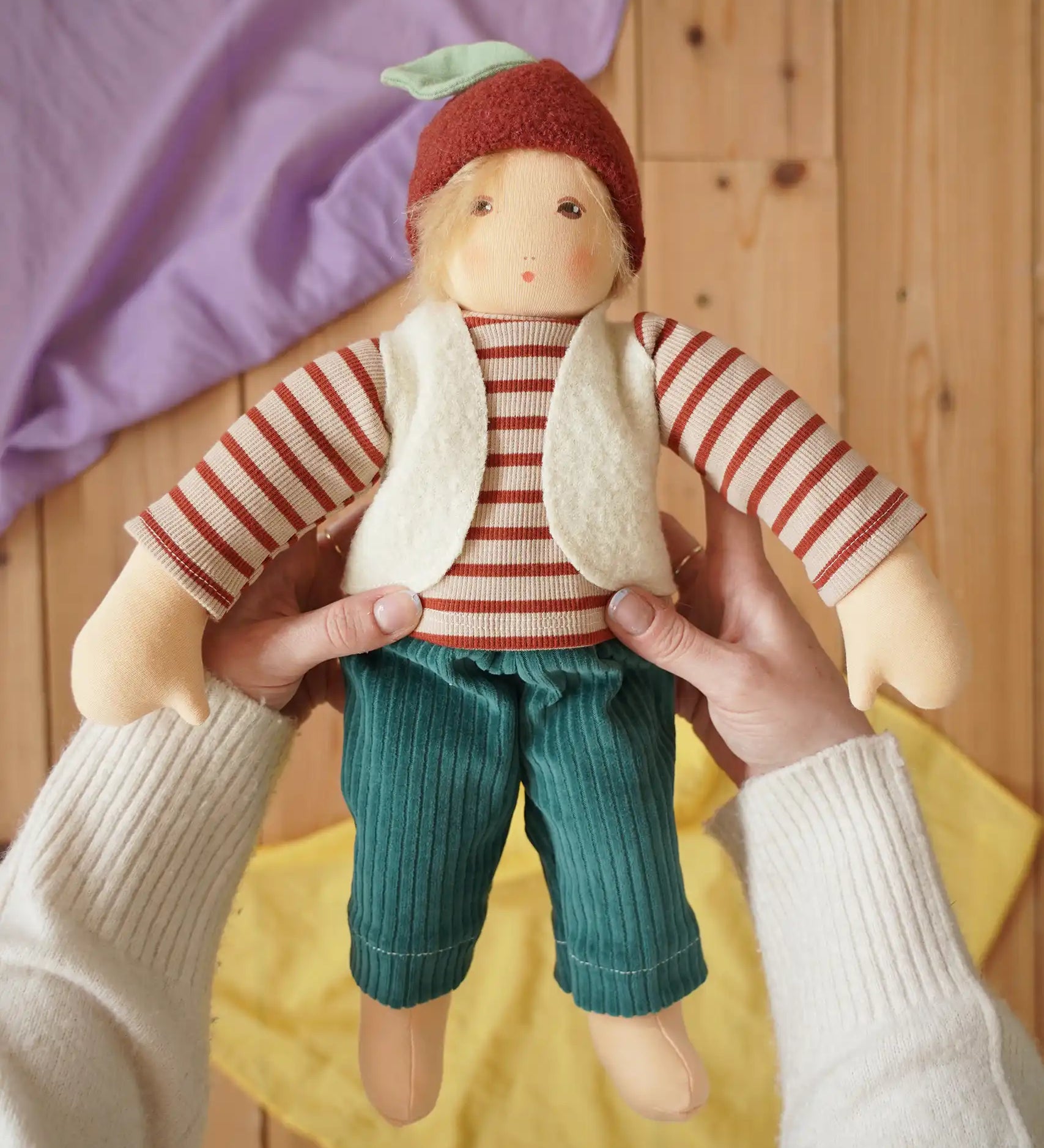 Nanchen Natur dress-up Waldorf doll chestnut child Paul in an adult's hands in the Babipur playroom.