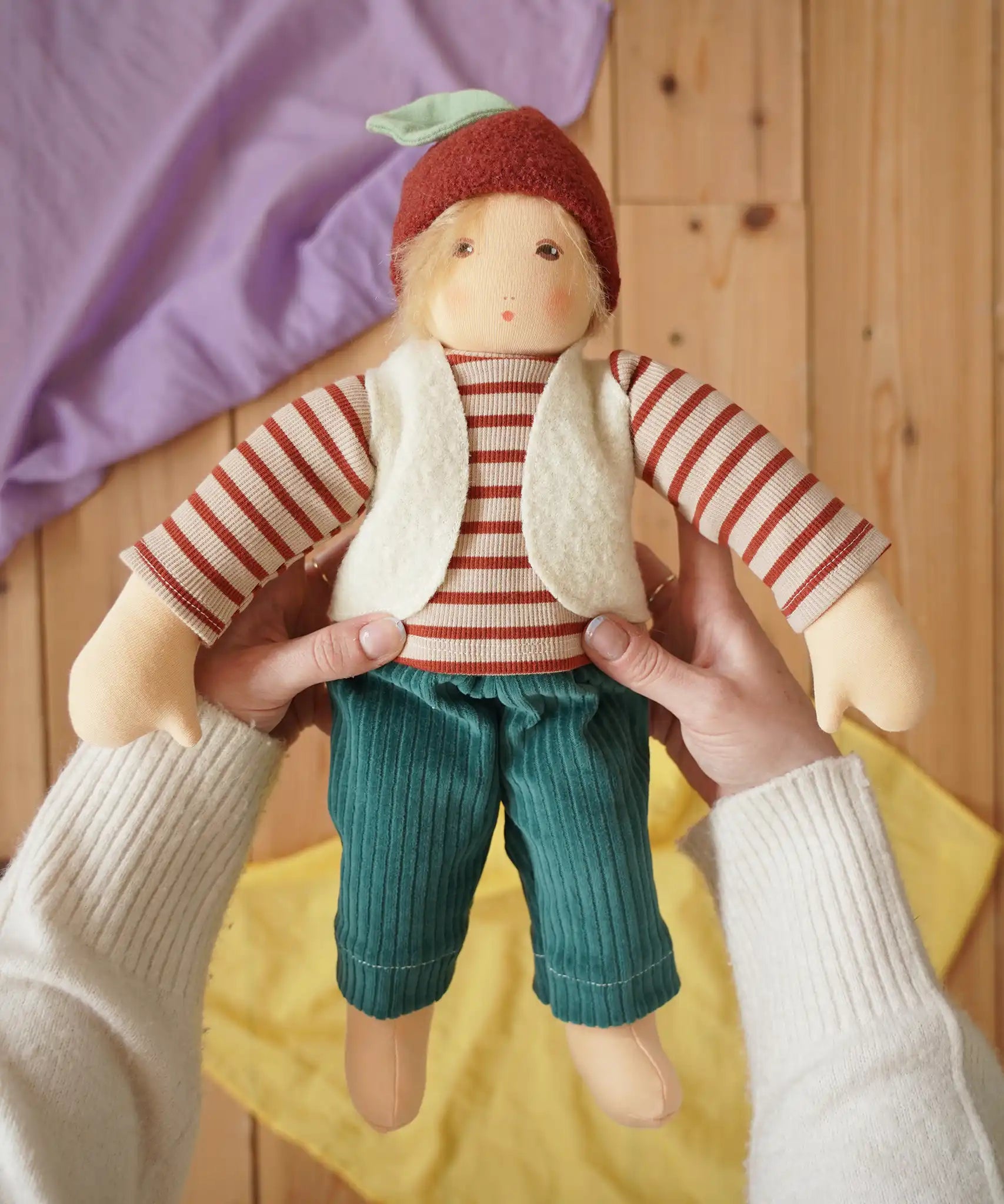 Nanchen Natur dress-up Waldorf doll chestnut child Paul in an adult's hands in the Babipur playroom.