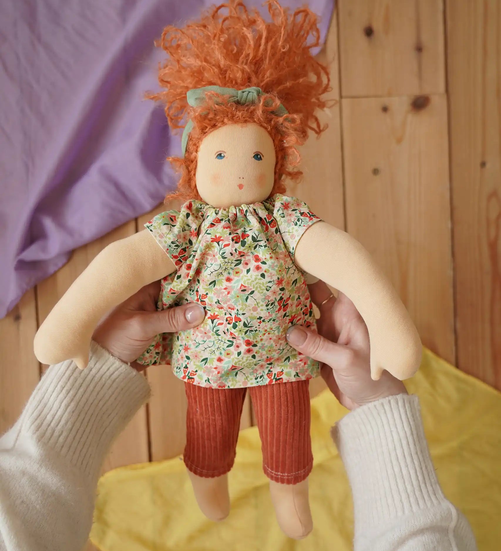 Nanchen Natur Flore Waldorf doll in an adult's hand in the Babipur playroom.