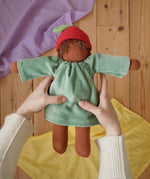 Nanchen Waldorf doll garden child Lilly with apple hat in an adult's hand in the Babipur playroom.