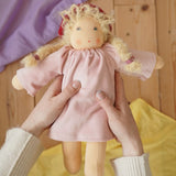 Nanchen Waldorf doll garden child Lolle with toadstool hat in an adult's hand in the Babipur playroom.
