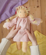 Nanchen Waldorf doll garden child Lolle with toadstool hat in an adult's hand in the Babipur playroom.
