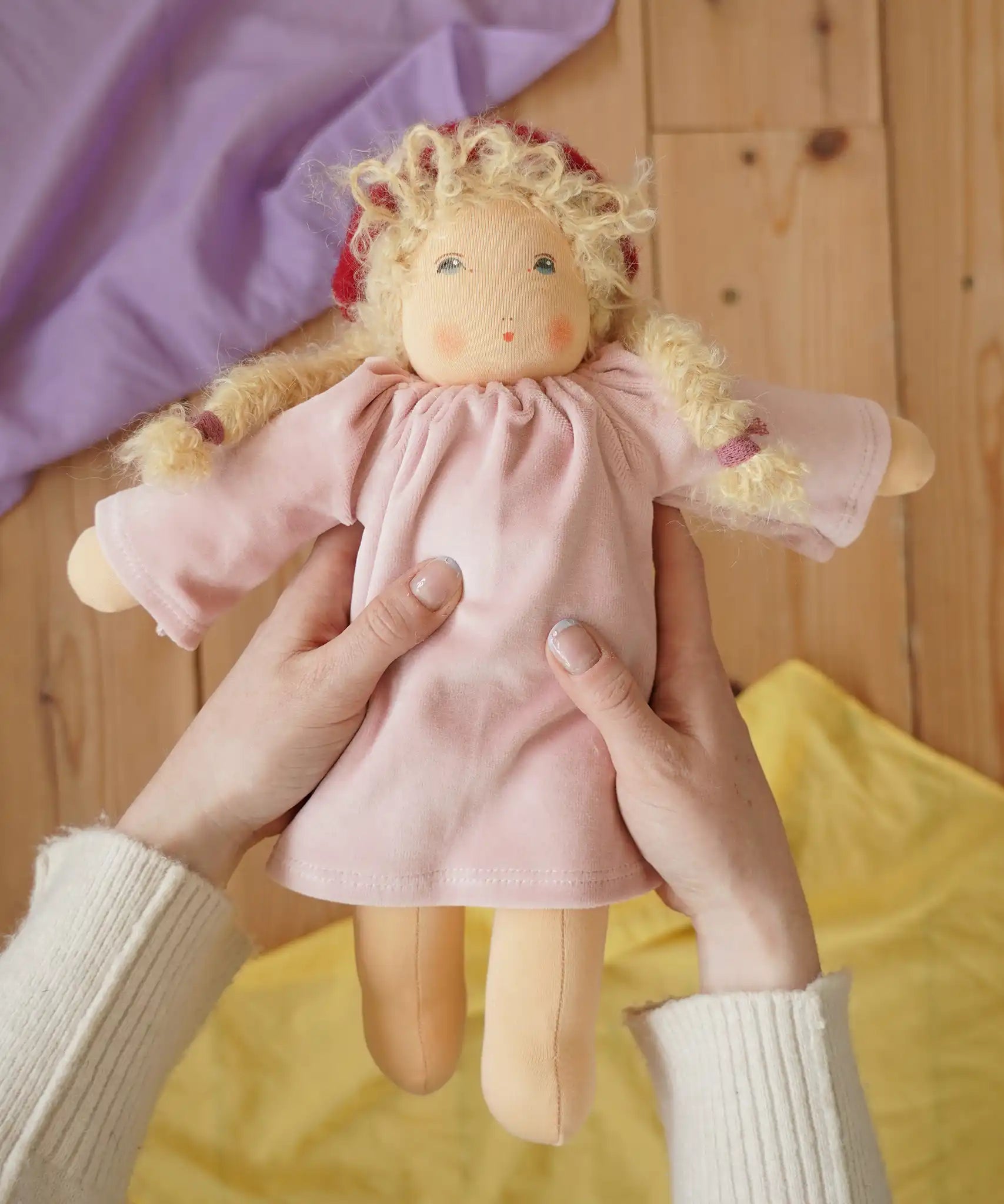 Nanchen Waldorf doll garden child Lolle with toadstool hat in an adult's hand in the Babipur playroom.
