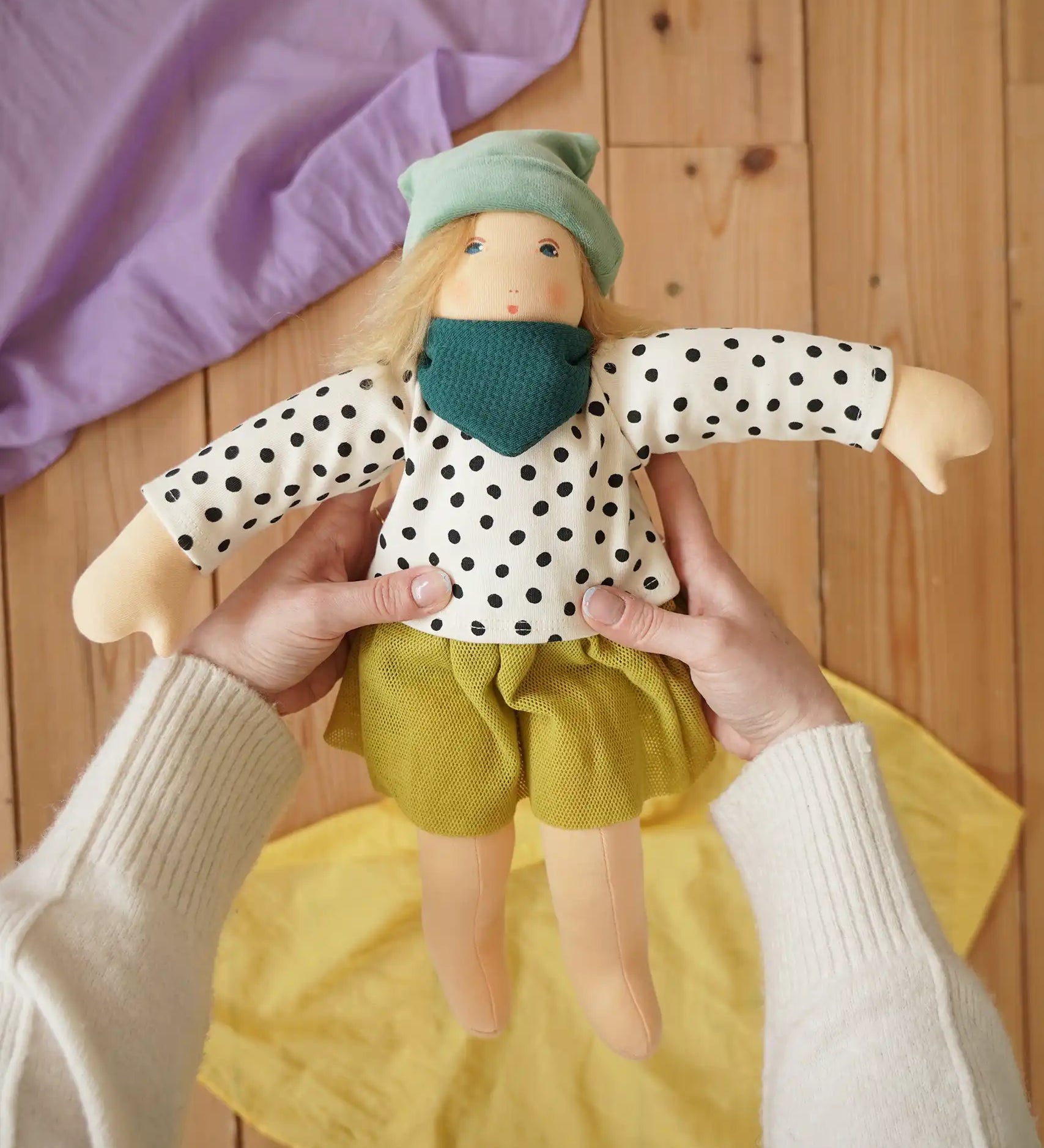 Nanchen Waldorf doll Mascha in an adult's hand in the Babipur playroom.
