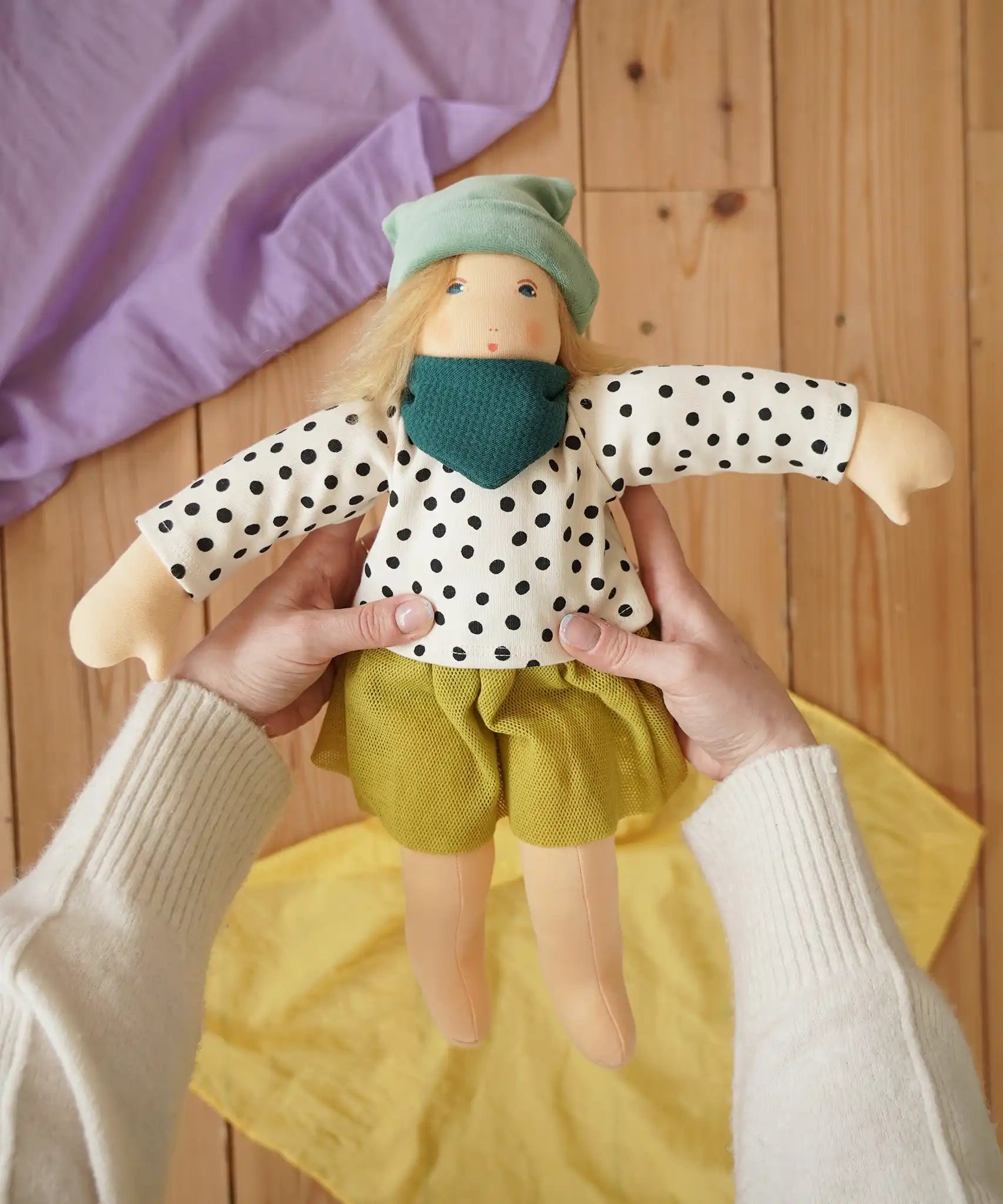 Nanchen Waldorf doll Mascha in an adult's hand in the Babipur playroom.
