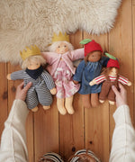 Four Nanchen organic Waldorf dolls, King Karl, Rossi and apple children placed on a wooden floor in the Babipur playroom. 