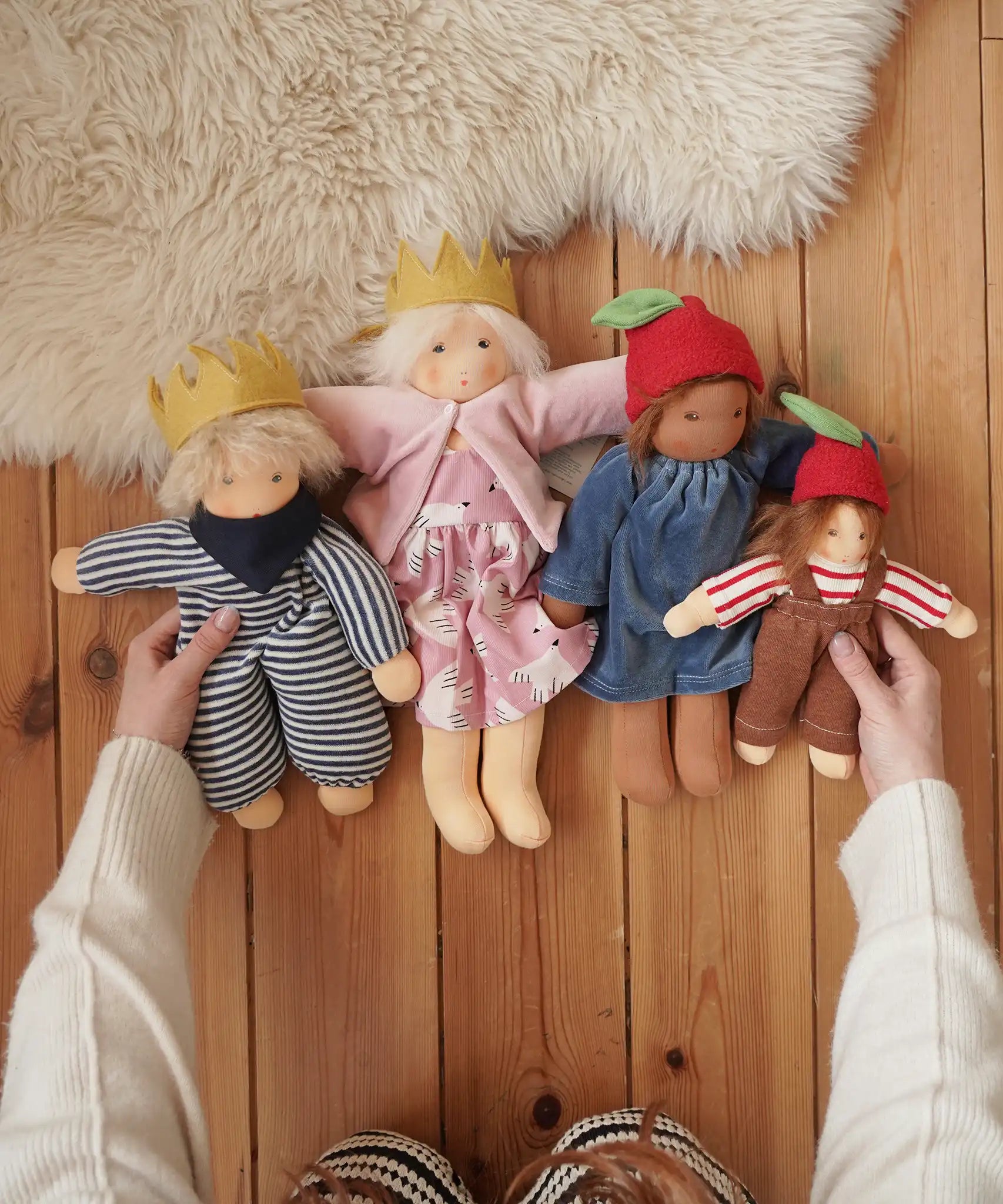 Four Nanchen organic Waldorf dolls, King Karl, Rossi and apple children placed on a wooden floor in the Babipur playroom. 