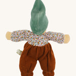 The back of the Nanchen Forest Child Waldorf Doll - Sage. This beautifully handcrafted doll wears sage velour trousers, a brown hat and a floral top. On a cream background