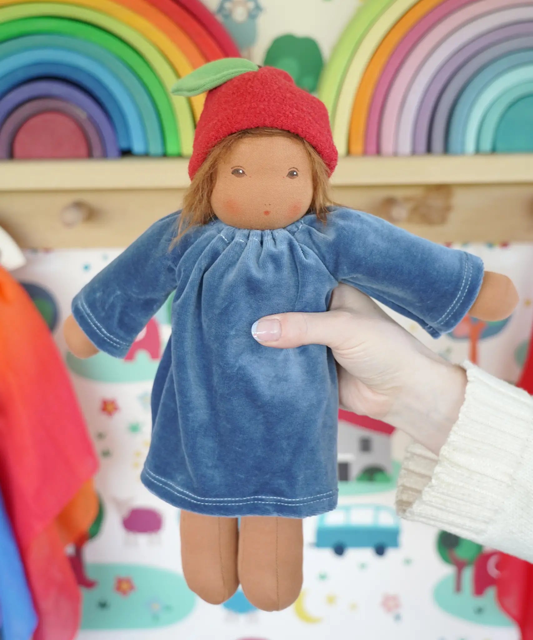 Adult hand holding a Nanchen Lenne garden child waldorf doll showing scale