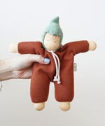 A close up of a Nanchen Walnut Baby Waldorf Doll in an adult's hand. 