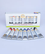 Natural Earth Paint acrylic classic studio paint set showing 8 aluminium tubes containing different coloured paints laid flat on a light surface next to the paint set packaging. 