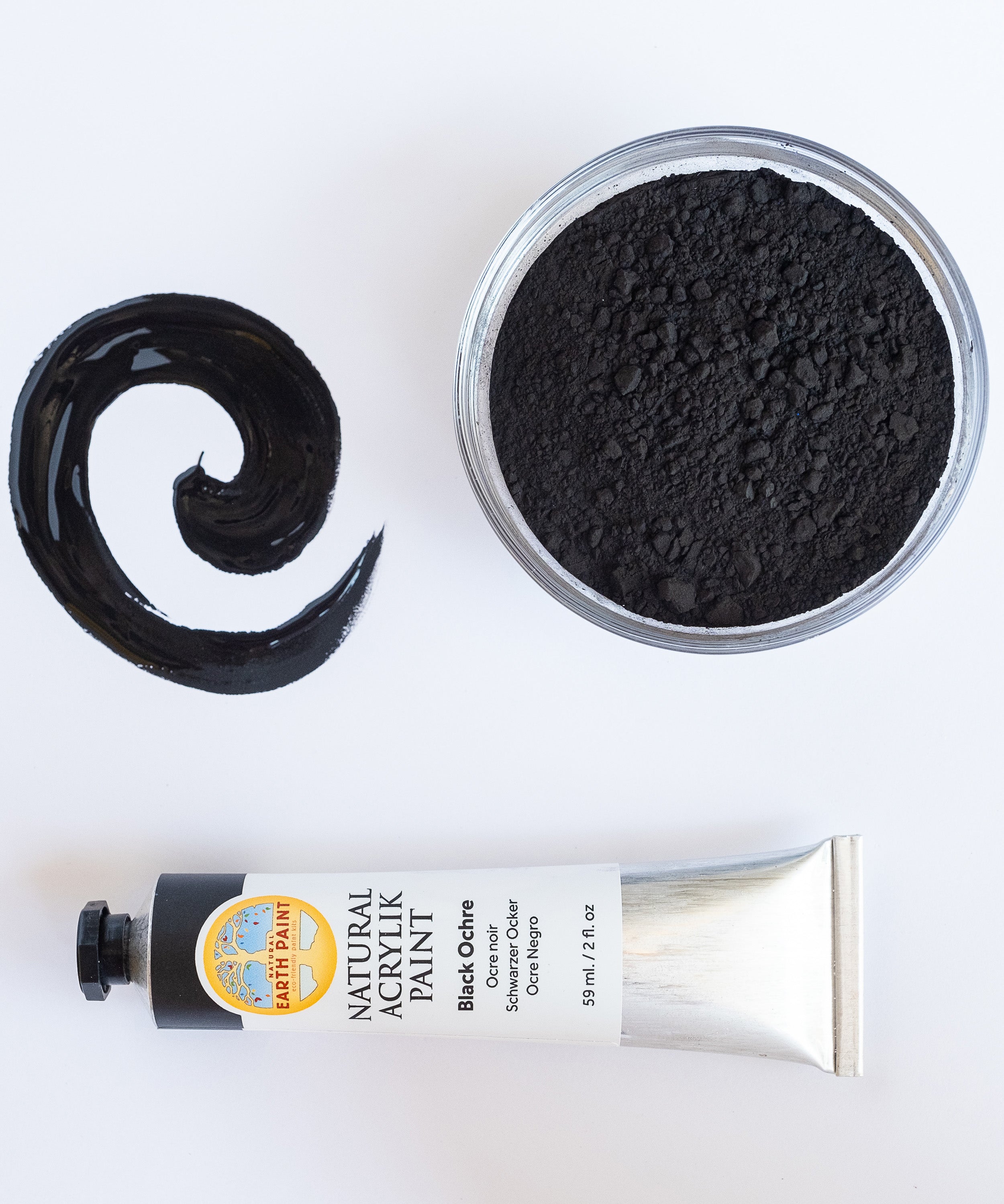 A top down view of the Natural earth paint in black ochre next to a bowl of black pigment and a paint streak showing the consistency. 