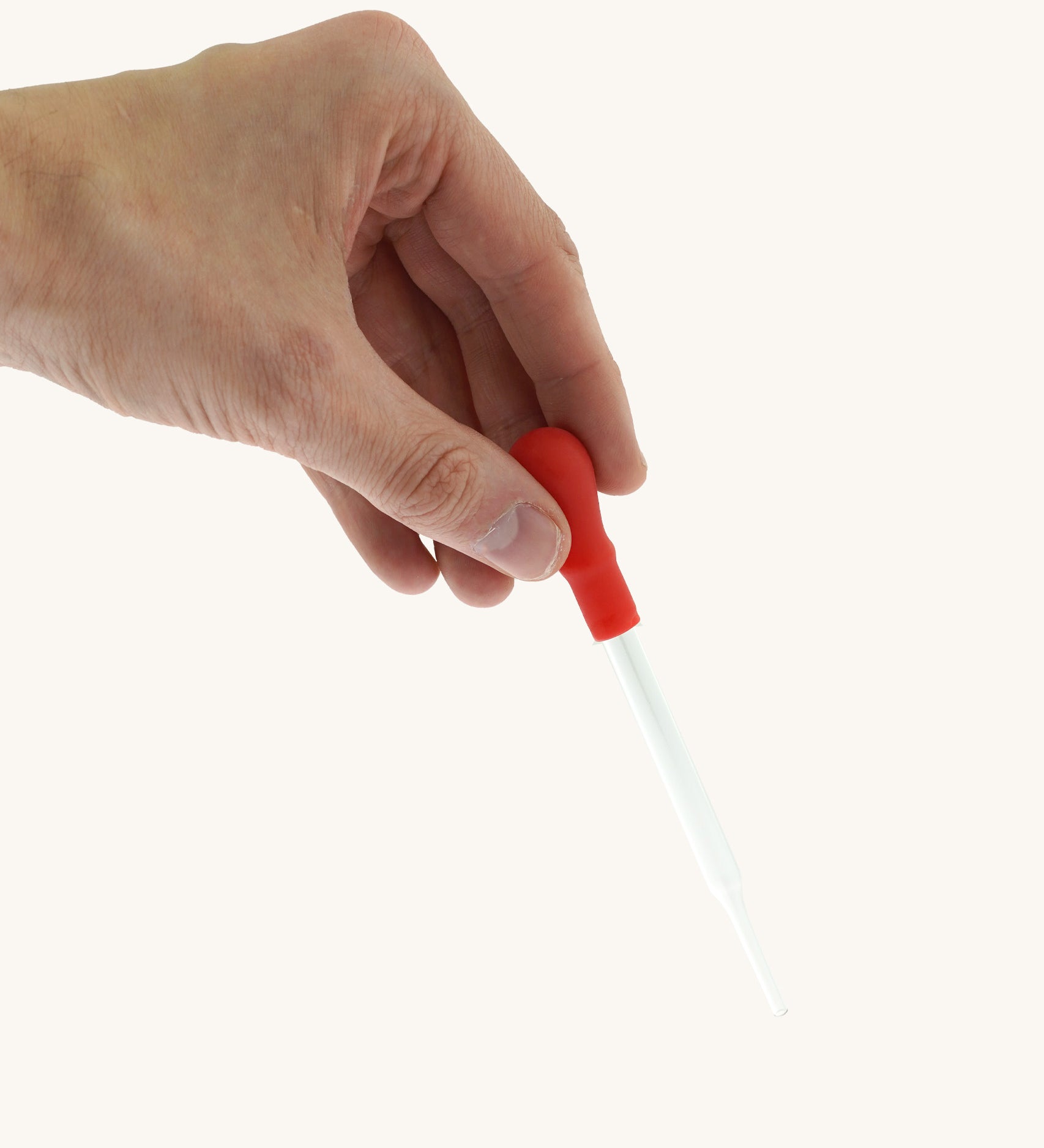 A adult hand holding the Natural Earth Paint glass dropper by the red squeeze handle for size reference