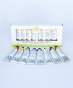 Natural Earth Paint acrylic paint set  showing 8 aluminium tubes containing different coloured paints laid flat on a light surface next to the paint set packaging. 
