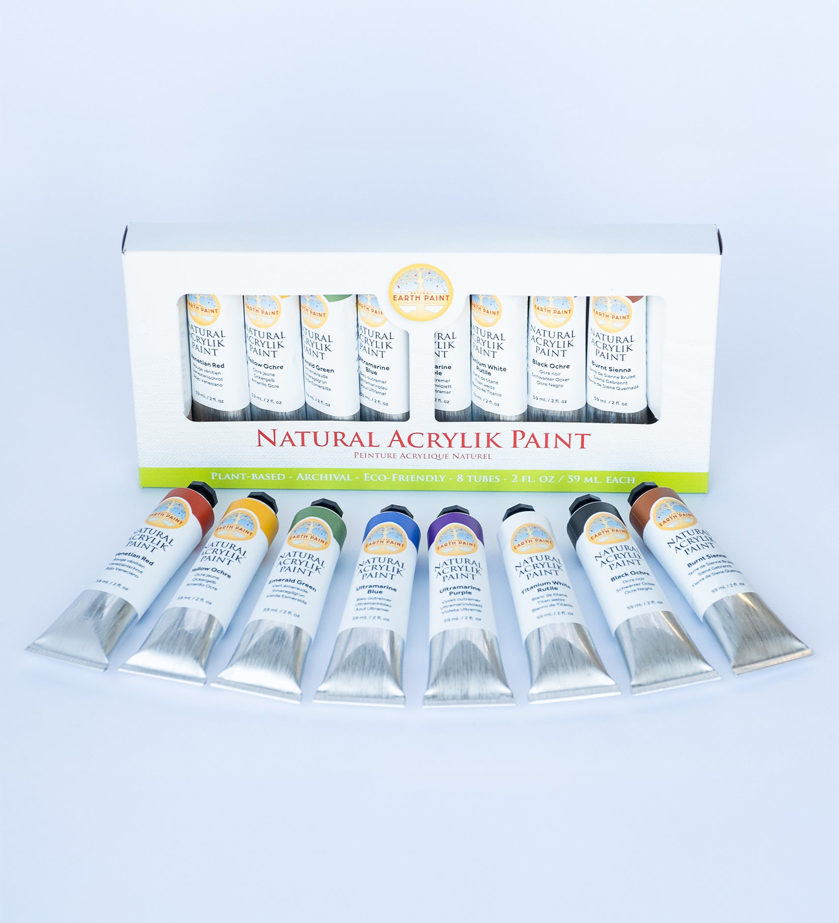 Natural Earth Paint acrylic paint set  showing 8 aluminium tubes containing different coloured paints laid flat on a light surface next to the paint set packaging. 