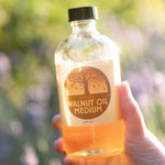 A adult hand holding A 8oz jar of Natural Earth Paint walnut oil 