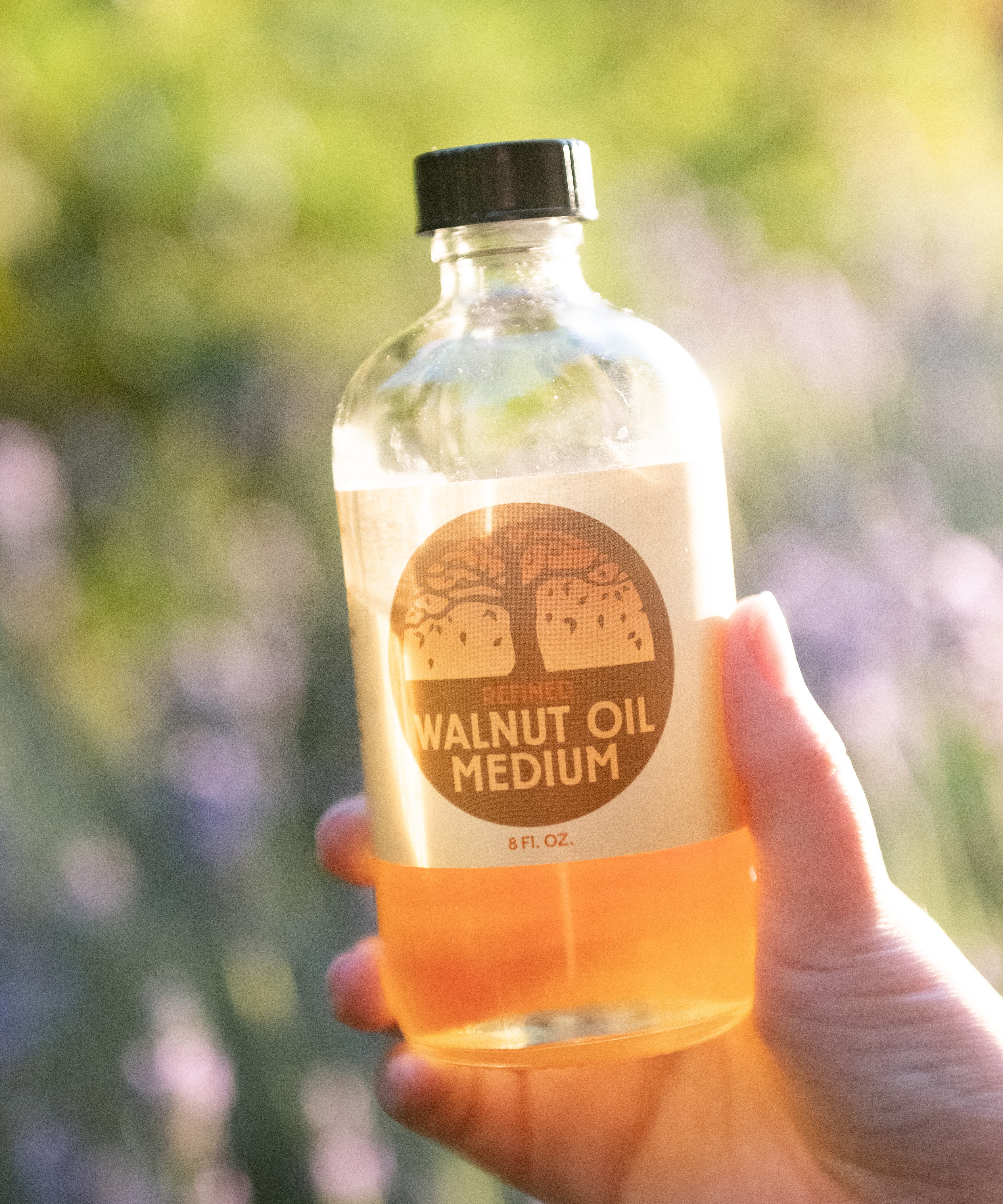 A adult hand holding A 8oz jar of Natural Earth Paint walnut oil 