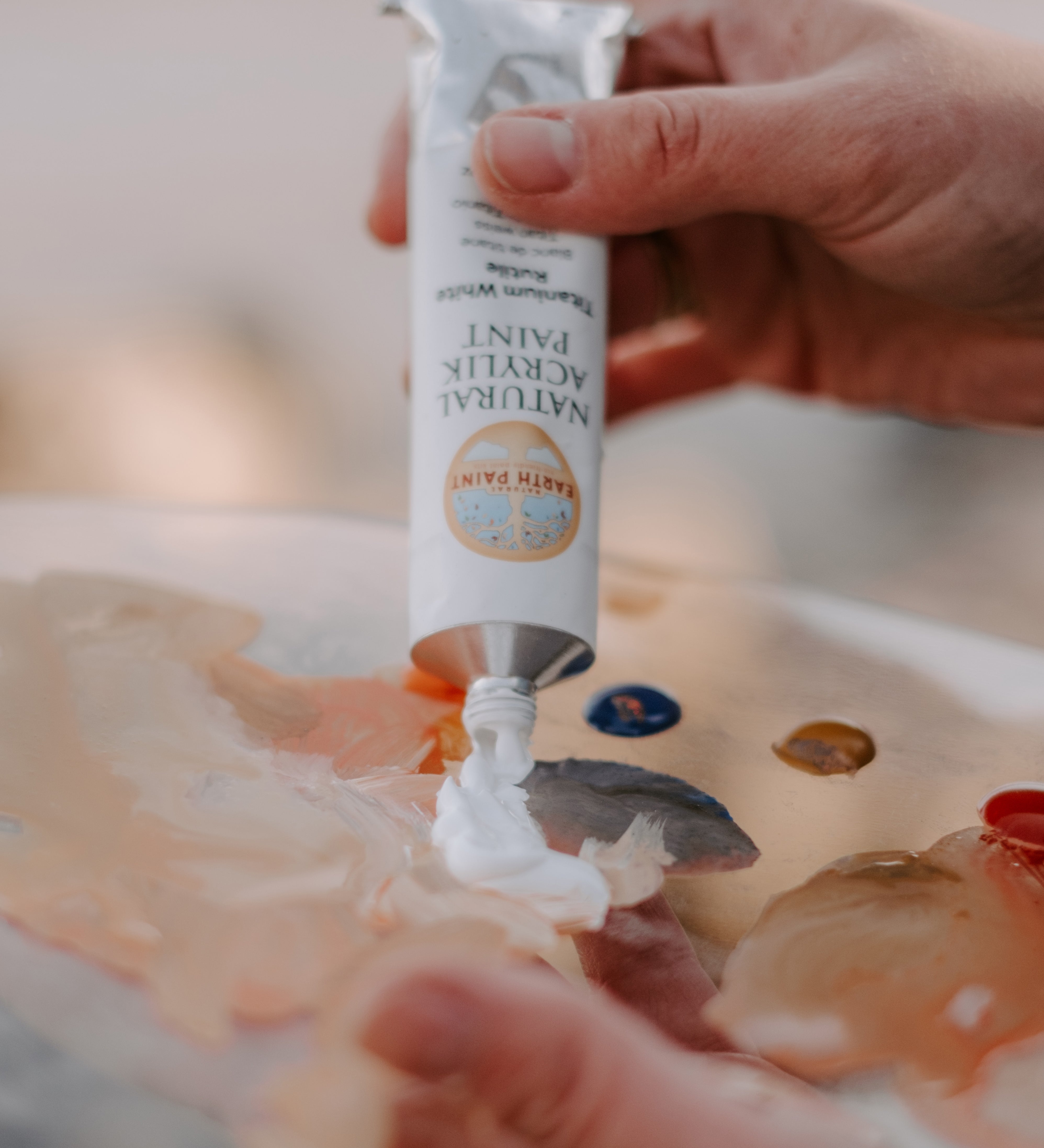 An artist hand squeezing the aluminium tube with white natural acrylic paint coming out from it