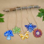 Wooden shapes from the Natural Earth Paint Nature Craft Paint Kit painted and hung from a branch. 