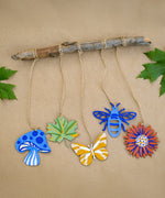 Wooden shapes from the Natural Earth Paint Nature Craft Paint Kit painted and hung from a branch. 