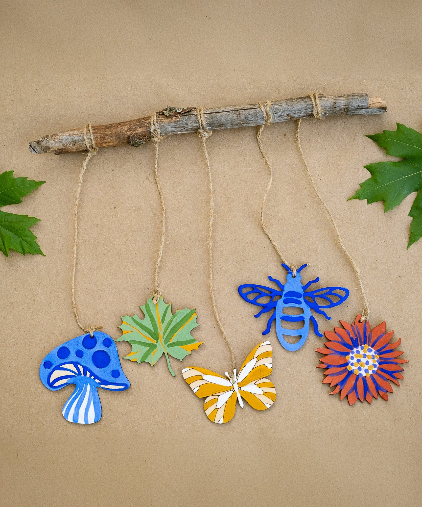 Wooden shapes from the Natural Earth Paint Nature Craft Paint Kit painted and hung from a branch. 