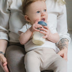 A baby drinking from the Lola & Lykke Natural Flow Baby Bottle with cap.