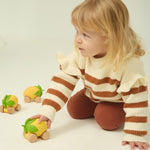 A child wheeling the Oli & Carol Lou the Lemon car across the ground