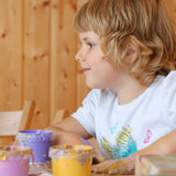 A child mixing the Neogrun crystal finger paint with their hand on a table