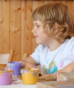 A child mixing the Neogrun crystal finger paint with their hand on a table