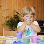 A child holding it's hands together with the Neogrun gold and purple finger paints mixing new colours for crafting