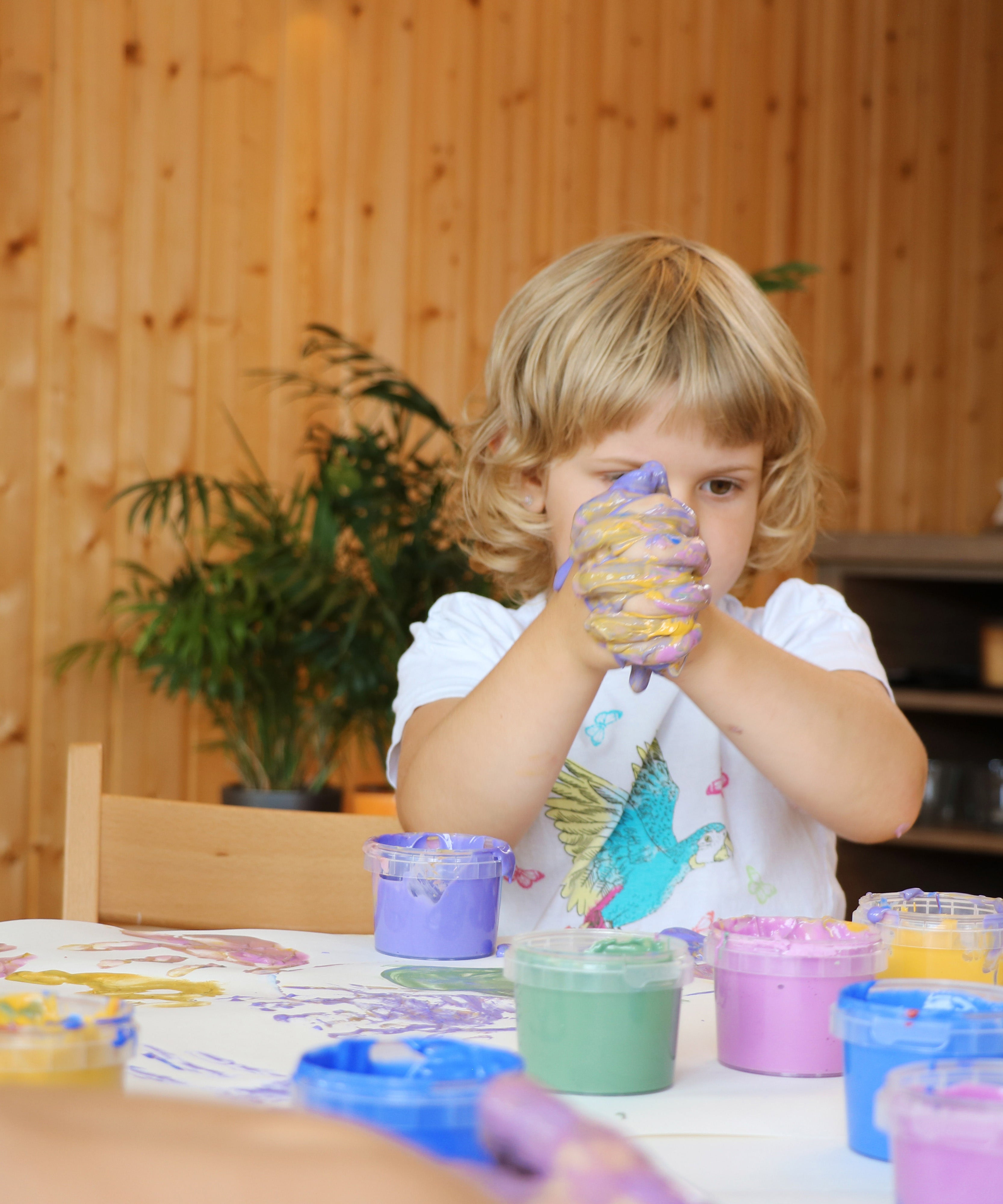 A child holding it's hands together with the Neogrun gold and purple finger paints mixing new colours for crafting
