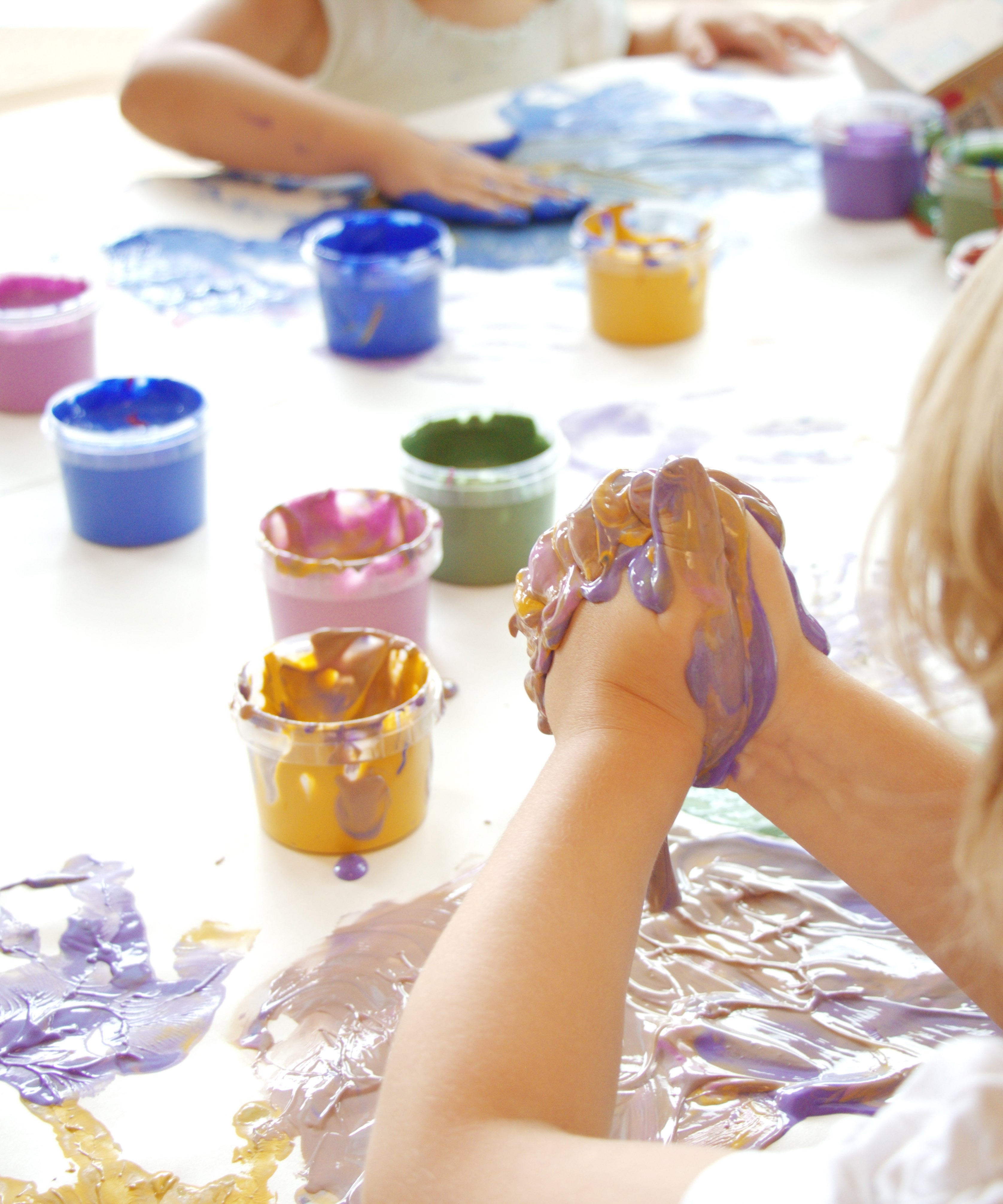A close up of a child's hand with the gold and purple Neogrun crystal finger paint mixed together showing the consistency of the paint