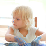 A close up of a child mixing different coloured Neogrun finger paints and making crafts