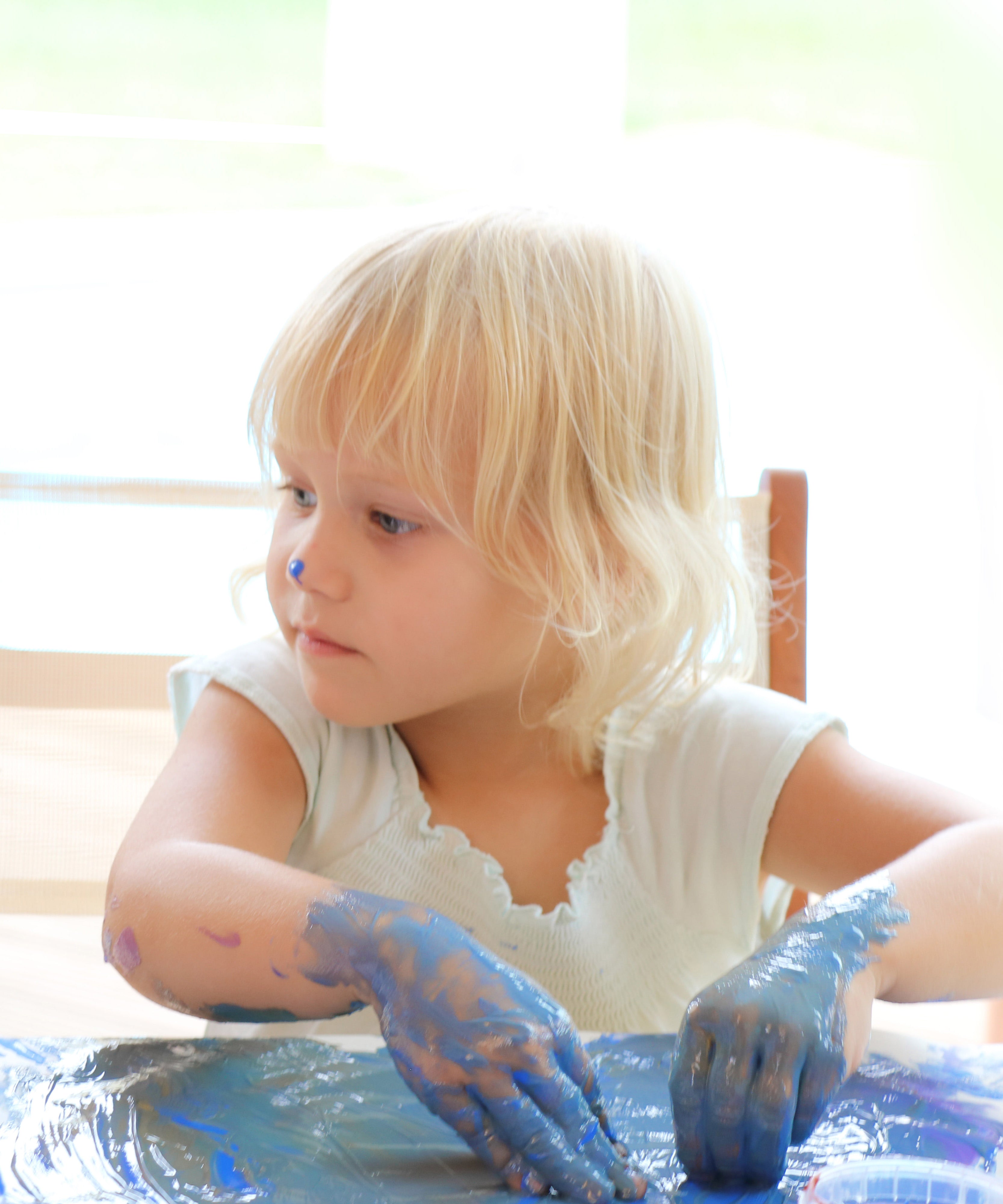 A close up of a child mixing different coloured Neogrun finger paints and making crafts