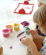 A child being creative with the purple Neogrun organic play dough on a table